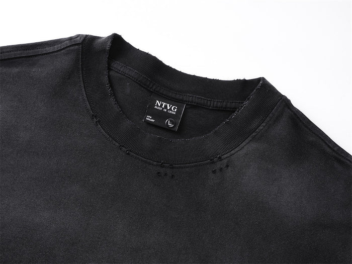 Close-up of the black tee’s ribbed crew neckline, distressed fabric, and sewn neck label
