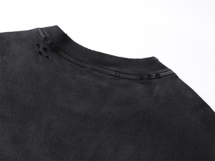 Close-up of the black tee’s ribbed crew neckline with distressed marks near the shoulder seam