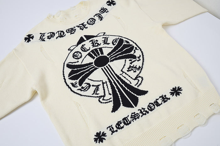 Angled close view of a cream knit sweater front with black cross graphic, Gothic lettering, and distressed hem