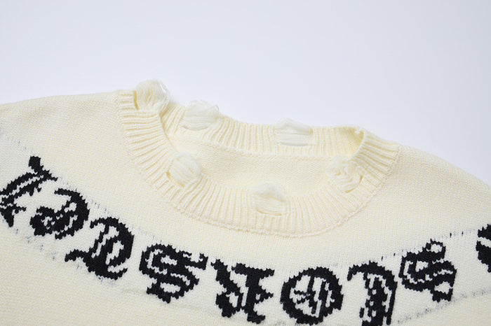 Close-up of the cream sweater ribbed collar and black Gothic shoulder lettering with distressed knit details