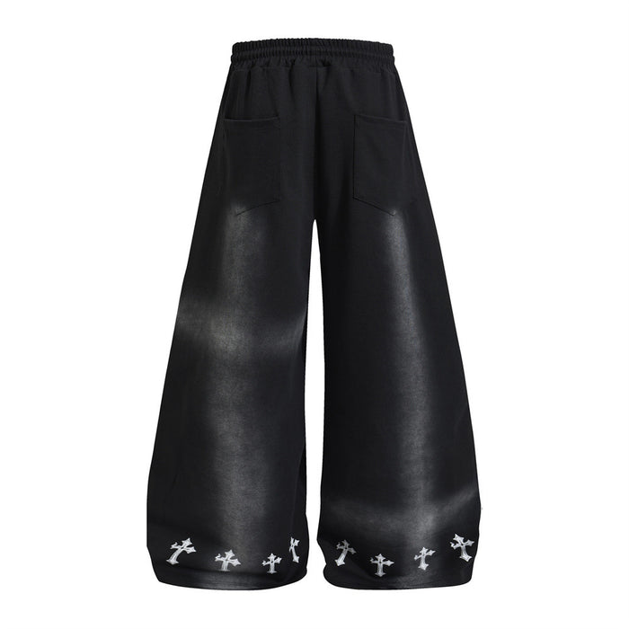 Back view of black wide-leg sweatpants with two patch pockets, gray shading, and small white cross prints at the hems