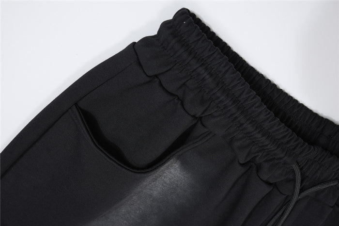 Close-up of the black sweatpants waistband and curved side pocket with visible stitching and drawstring opening