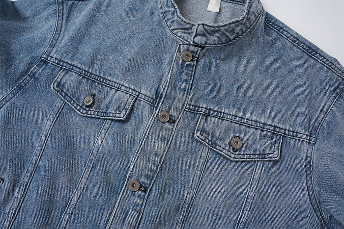 Close-up of the denim jacket front showing two flap chest pockets, metal buttons, and vertical seam details
