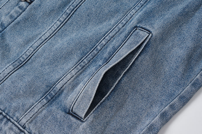 Close-up of a vertical side hand pocket opening on the washed blue denim jacket