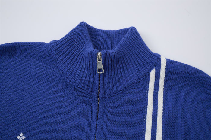 Close-up of the blue knit jacket's ribbed turtleneck collar, metal zipper, and white shoulder stripes