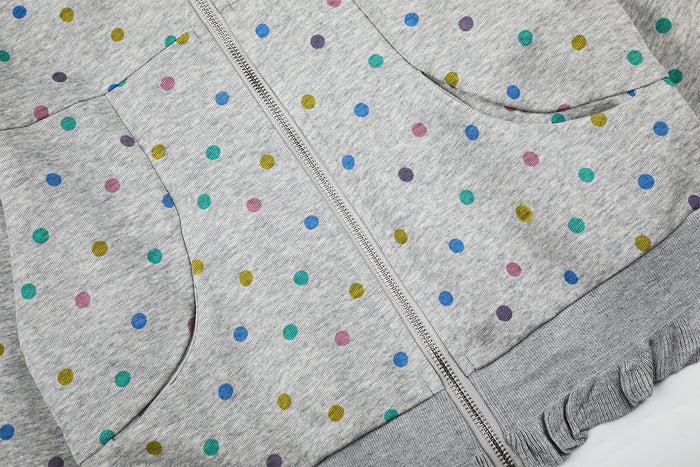 Close-up of the grey polka dot hoodie front showing the zipper, curved pocket edge, and ruffled lower hem