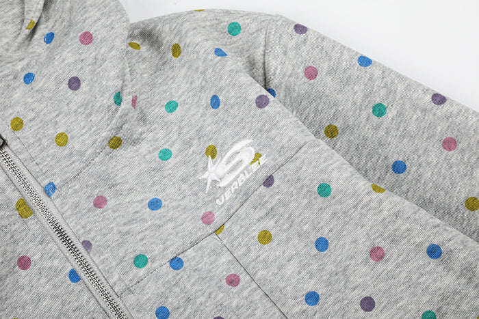 Close-up of the grey polka dot hoodie showing the front zipper, pocket seam, and small white chest emblem