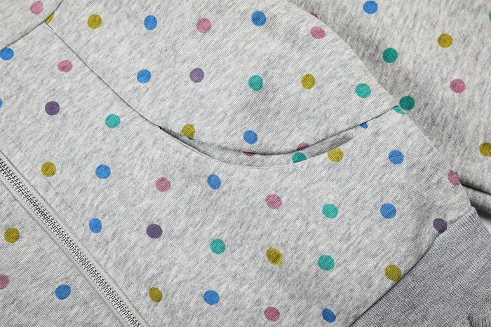 Close-up of the grey polka dot hoodie showing the curved front pocket seam and zipper edge
