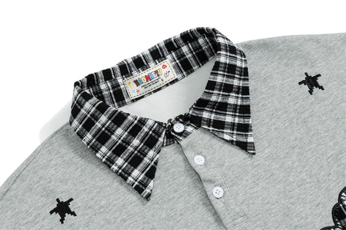 Close-up of the gray sweatshirt’s black-and-white plaid collar, button placket, and shoulder motif