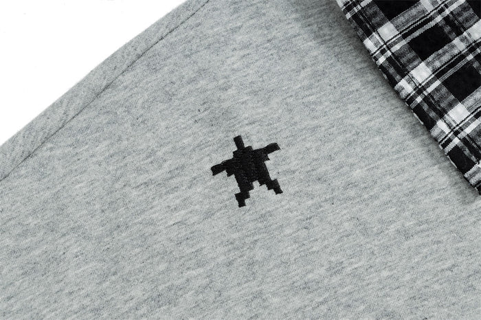 Close-up of the gray sweatshirt fabric showing a small black embroidered decorative motif