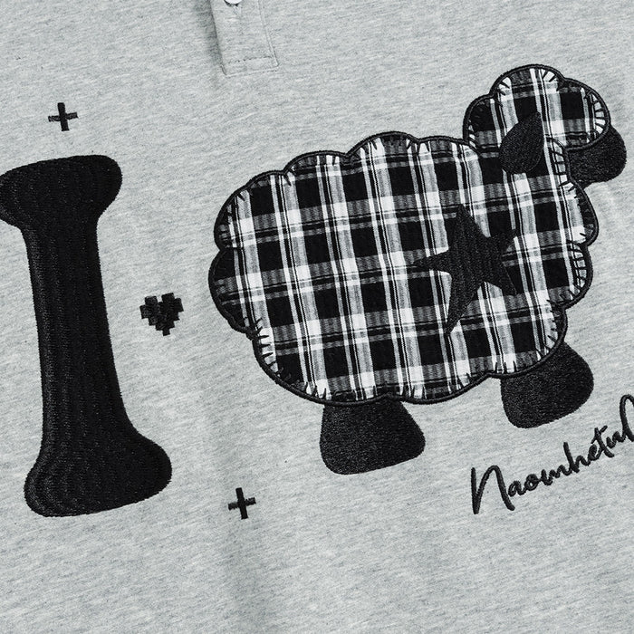 Close-up of the gray sweatshirt front showing a black-and-white plaid sheep appliqué beside a black graphic