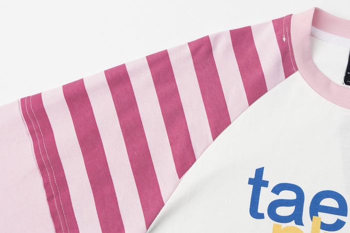 Detailed view of the pink striped raglan sleeve, seam stitching, pink cuff, and white neckline