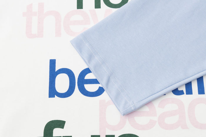 Close-up of the pale blue sleeve cuff over the white shirt front and blue printed lettering