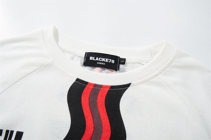 Close-up of the white jersey tee collar, shoulder seam, black-red wavy stripe, and sewn BLACKETE78 label