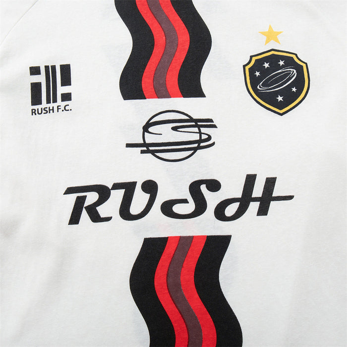 Front detail of the white jersey tee with RUSH lettering, black-red wavy stripes, team logos, and crest