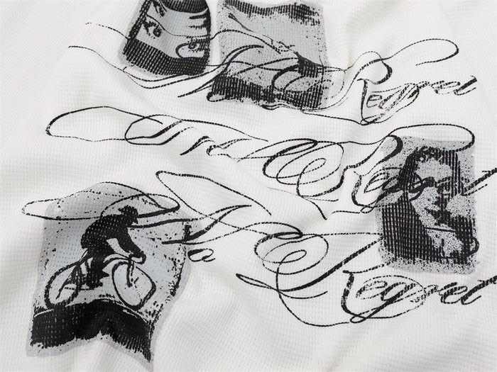 Close-up of black script lettering and grayscale illustrated panels printed on white waffle-knit fabric
