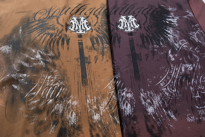 Close-up of tan and deep plum shirt fronts featuring large black and white wing graphics with script lettering