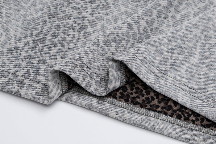 Close-up of layered gray shirt fabric and leopard-print sleeve fabric with visible stitching and folded edge
