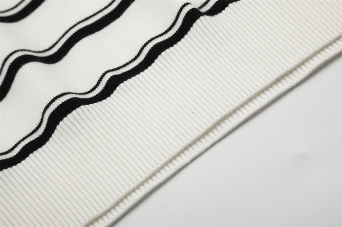 Close-up of the white ribbed sweater hem with horizontal black stripe detailing