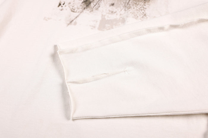 Close-up of the off-white shirt hem showing double stitching and a folded edge