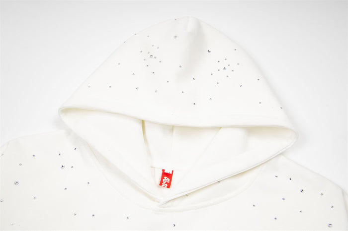 Close-up of the white hoodie hood opening with scattered rhinestones and a red neck label