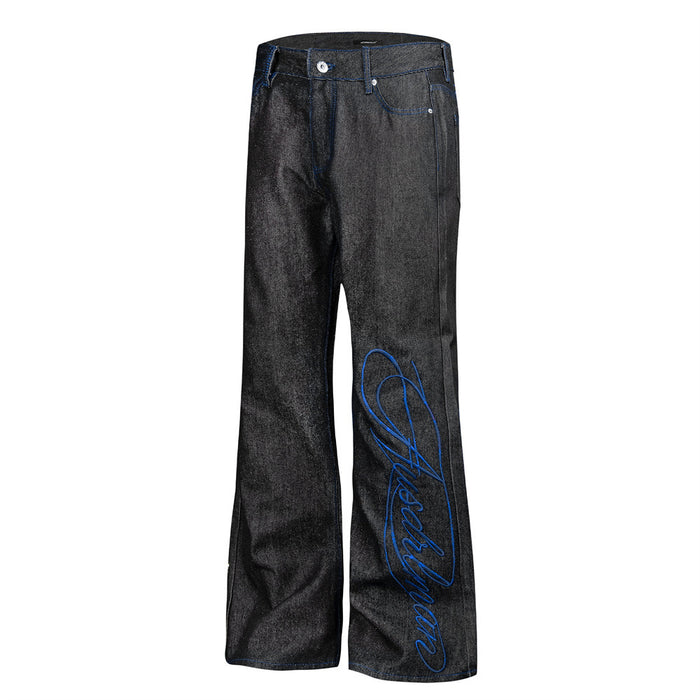 Angled front view of black bootcut jeans featuring blue script embroidery along one leg
