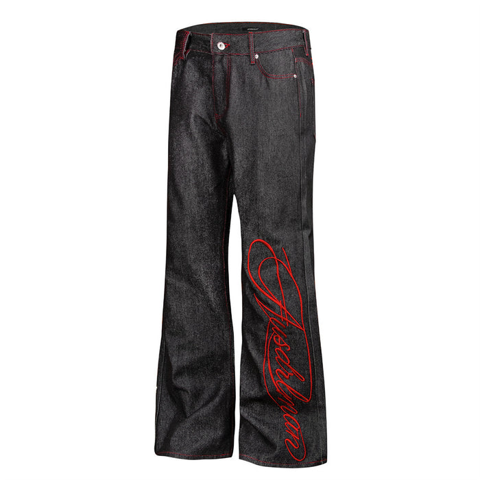 Angled front view of black bootcut jeans featuring red script embroidery along one leg