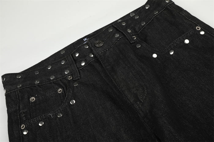 Close-up of the black jeans waistband and front pockets decorated with silver studs