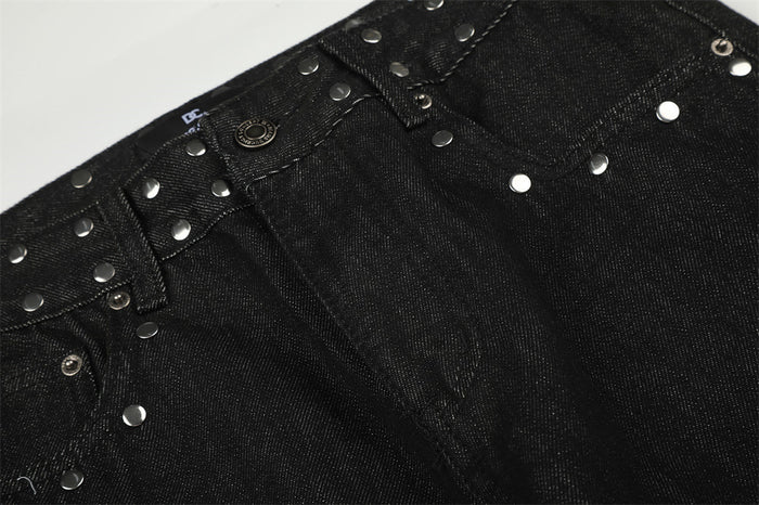 Detailed view of the black denim front waist, button fastening, belt loops, and scattered silver studs
