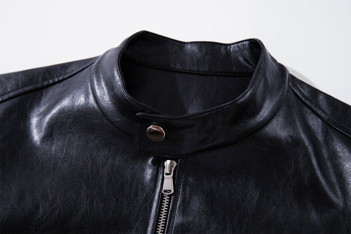 Close-up of the black moto jacket's stand collar, snap fastening, and central metal zipper