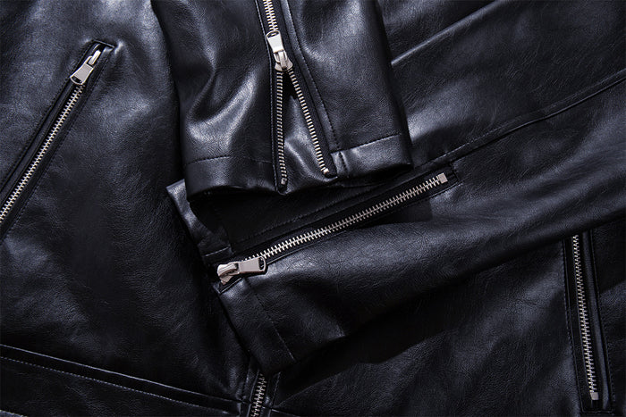 Close-up of black faux leather jacket pockets and metal zippers across the front and sleeve