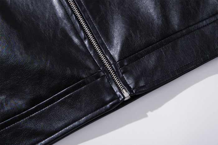 Close-up of the jacket's central zipper meeting the lower hem on smooth black faux leather