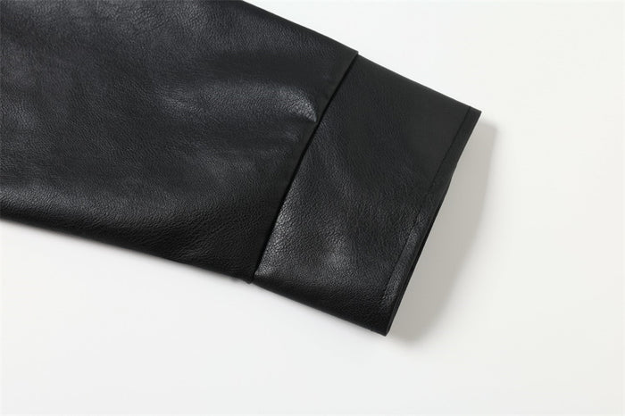 Close-up of black leather-look polo sleeve showing smooth texture, stitched cuff and panel seam