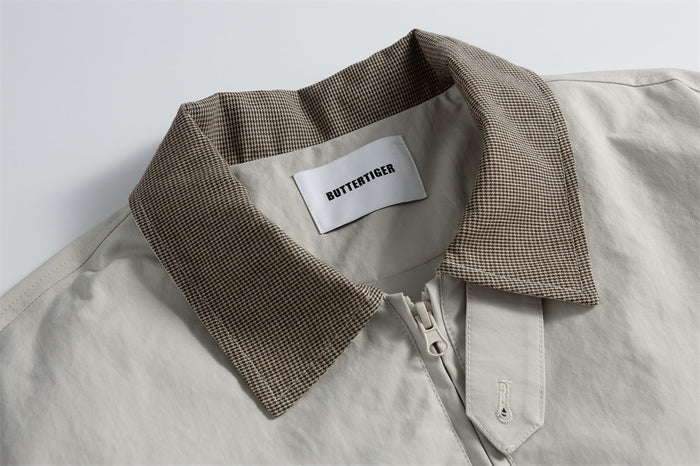 Close-up of the light gray jacket's brown houndstooth collar, inner label, and front zipper