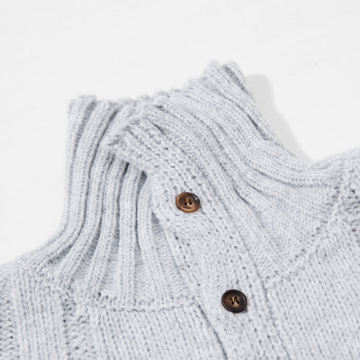 Close-up of the light gray ribbed mock neck and brown buttons on the sweater placket