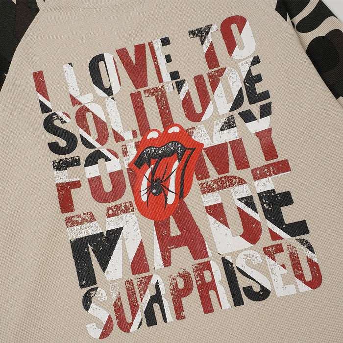 Close-up of distressed red, white, and black lettering with a red lips and spider graphic on beige knit fabric