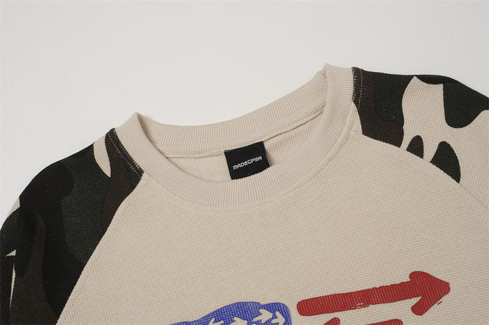 Close-up of the beige shirt collar, waffle-knit texture, camouflage shoulder panels, and partial arrow graphic