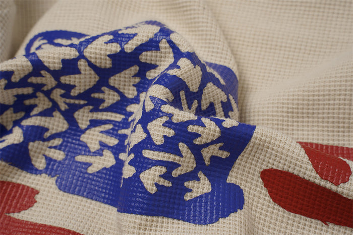 Detailed view of the blue printed graphic and red arrows over textured beige waffle-knit fabric