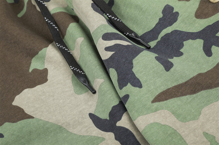 Close-up of black drawstrings against the green and brown camouflage sweatpants fabric