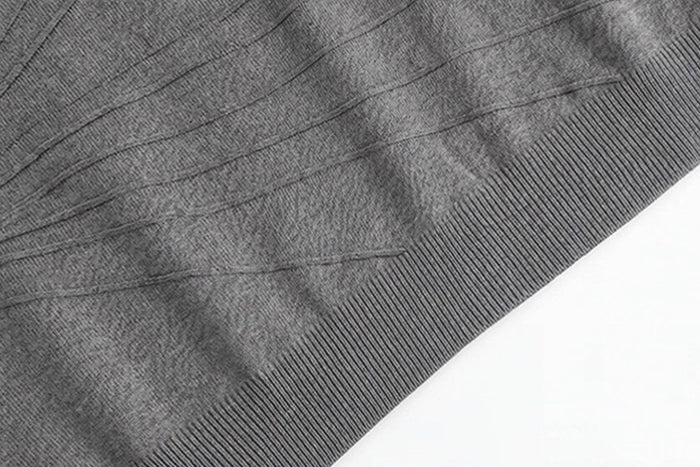 Close-up of gray sweater knit detail showing radiating raised lines above the ribbed hem