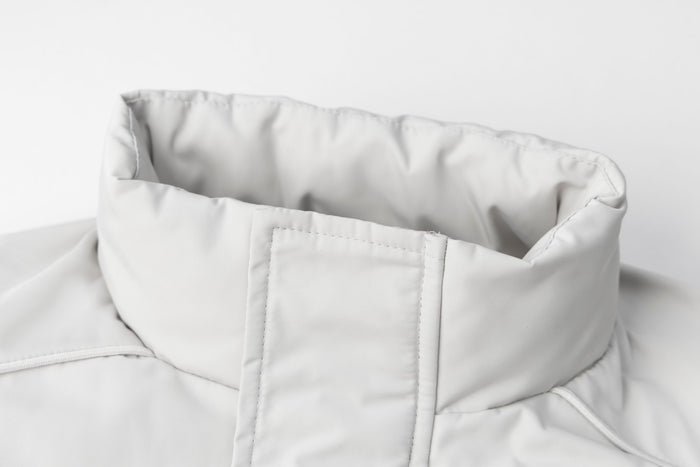 Close-up of the white bomber jacket's padded stand collar and central front zipper placket
