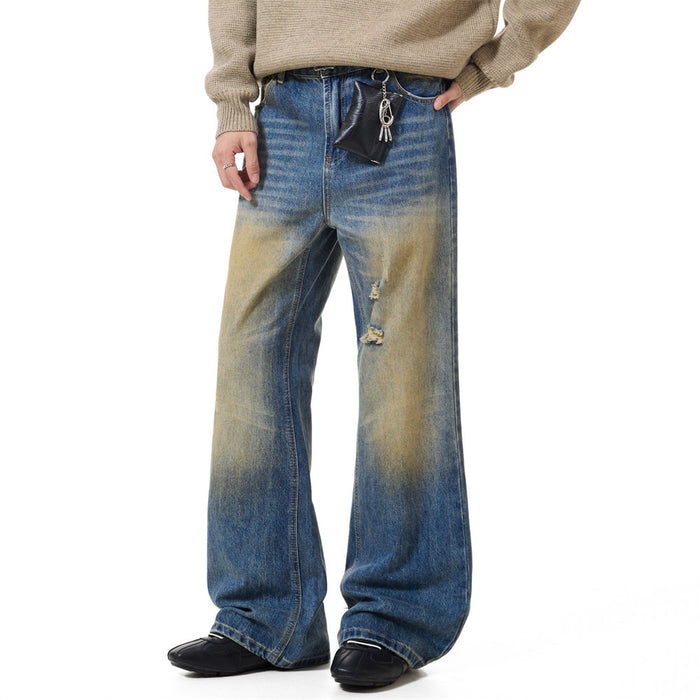 Front view of blue wide-leg jeans with tan faded patches, distressed thigh details, and flared hems worn with a sweater