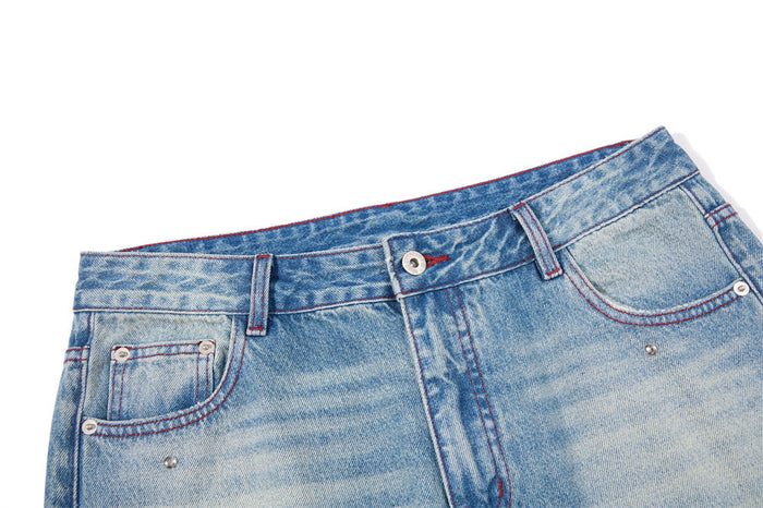 Close-up of the jeans waistband, belt loops, button fastening, front pockets, and red stitching