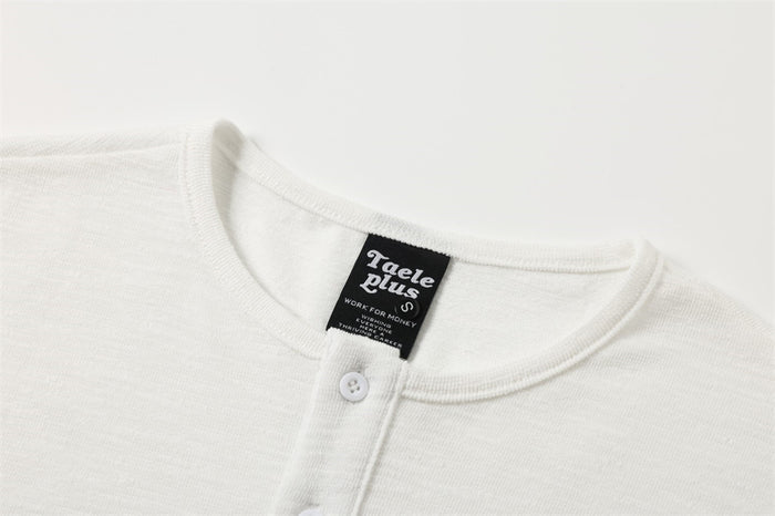 Close-up of the white Henley collar, button placket, and black neck label