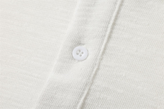 Close-up of a white button on the Henley placket, showing the shirt's fine textured fabric