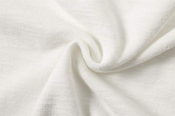 Draped white shirt fabric showing its fine textured weave and soft folds