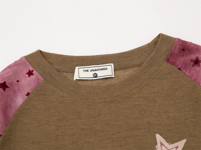 Close-up of the brown shirt neckline showing the ribbed collar, sewn label, and pink star-print sleeves