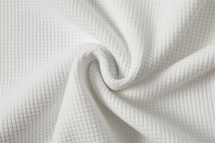 White waffle-knit shirt fabric gathered into folds to show its raised textured weave