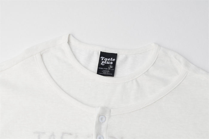 Close-up of the white shirt’s crew neckline, button placket, and sewn neck label