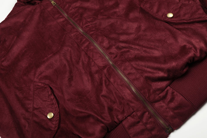 Close-up of the burgundy jacket front showing the metal zipper, flap pocket, and ribbed waistband